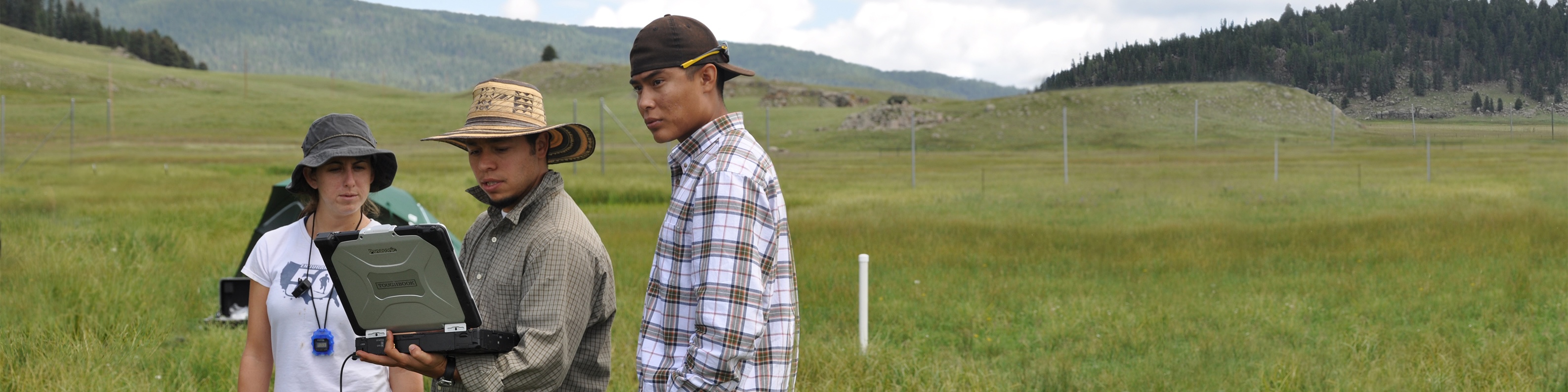 researchers standing in the valle grande looking at computer