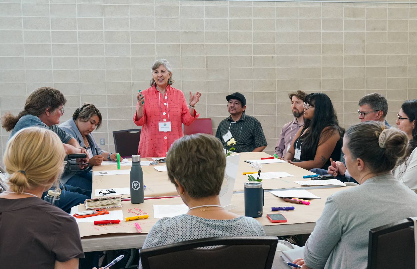 a woman speaking at a table of people