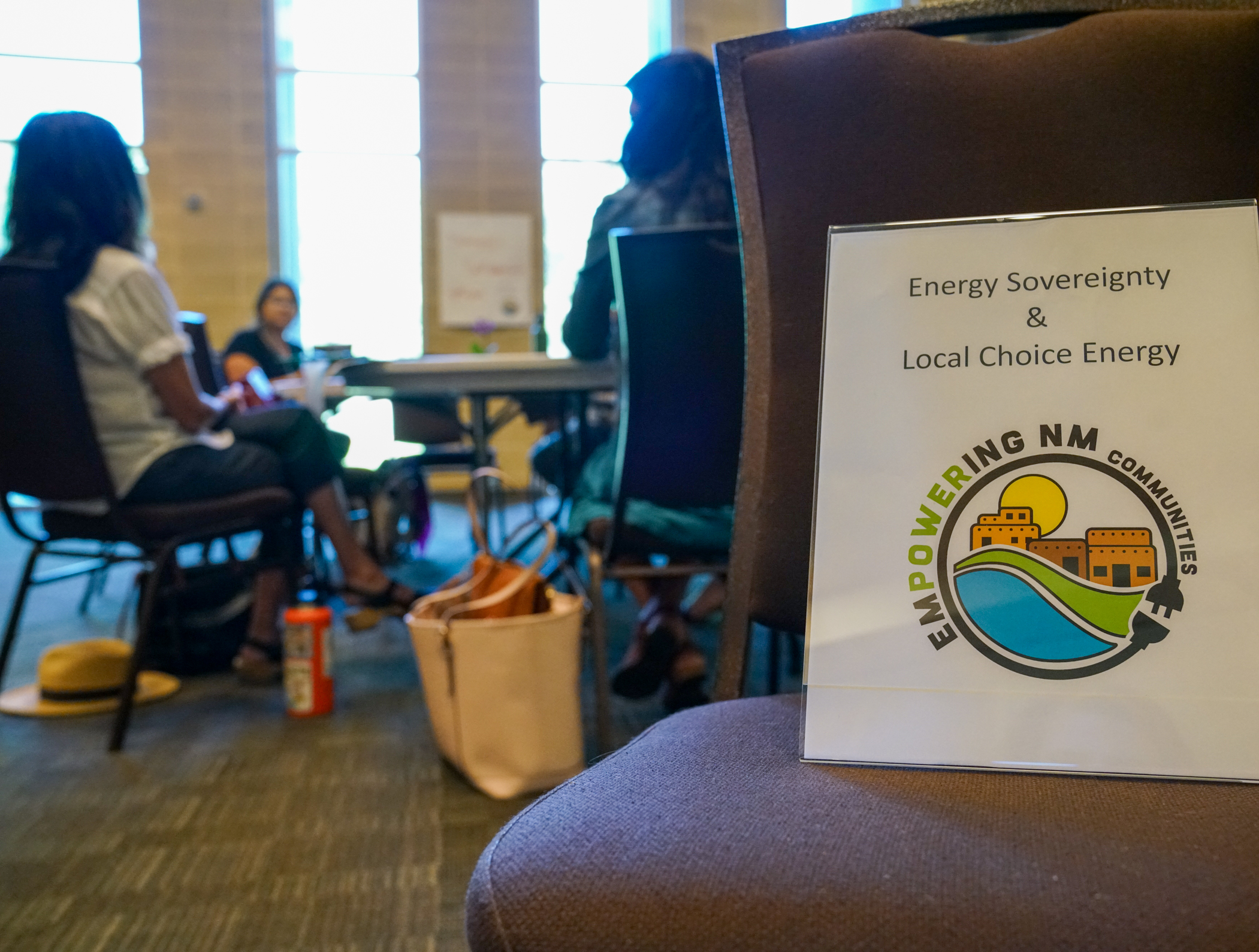 Sign on a chair with people talking in the background