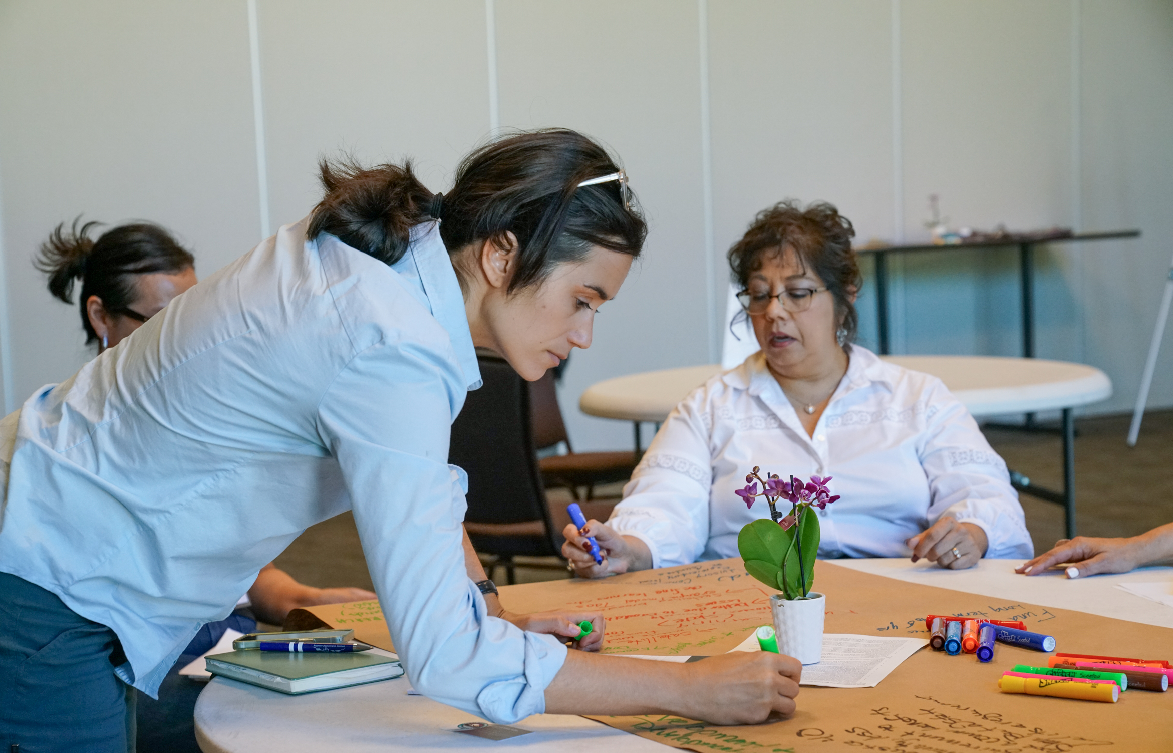 Woman writing on large paper on a table